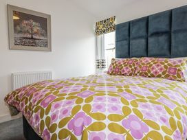 A bedroom with a bed and framed picture at Minack Lodge in Redruth