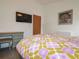 A bedroom with a bed, desk, tv and picture at Minack Lodge in Redruth