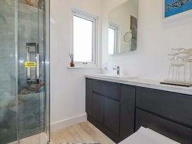 A bathroom with a shower, sink, and mirror at Minack Lodge in Redruth