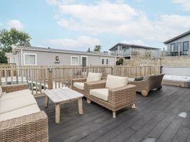 An outdoor terrace with seating and a hot tub at Minack Lodge in Redruth