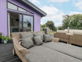 An outdoor area with a sofa and glass door at Minack Lodge in Redruth