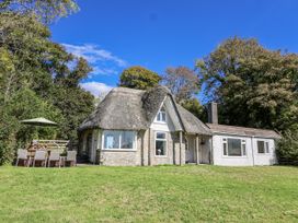 A thatched roof cottage with outdoor seating at Tapps Lodge Brixton near Yealmpton, South Devon