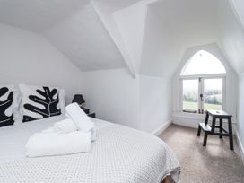A bedroom with a bed and an angled window at Tapps Lodge Brixton near Yealmpton, South Devon