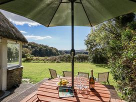 A garden table with an umbrella, bottle, and glasses at Tapps Lodge in Brixton near Yealmpton, South Devon