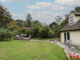 A garden with a house and deck area containing a hot tub at Harran in Pershore