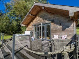 A wooden cabin with outdoor furniture and a hot tub at Dwrgi in Llanybydder