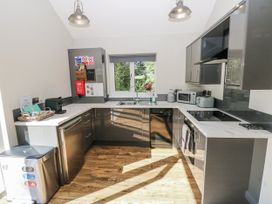 A kitchen with sink, fridge, and appliances at Dwrgi in Llanybydder