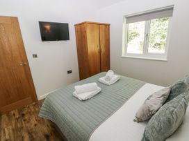A bedroom with a bed, towels, wardrobe and a television at Dwrgi in Llanybydder