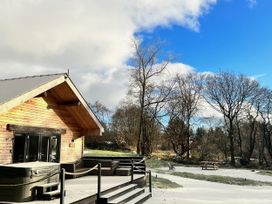 A wooden cabin with a deck and hot tub in a snowy outdoor area at Dwrgi Aber near Llanybydder