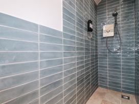 A shower area with blue tiles and a showerhead at The Old Dairy 