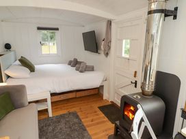 A sleeping area with a bed and stove at Shepherd's Hut in Perranarworthal