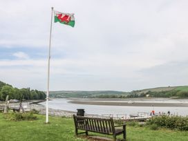A bench by the water with a flag at Penally Mews in St Dogmaels