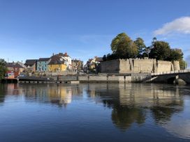 A view of a castle and buildings by a river at Penally Mews St Dogmaels