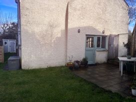 A garden with grass, patio, table and planters at Penally Mews in St Dogmaels