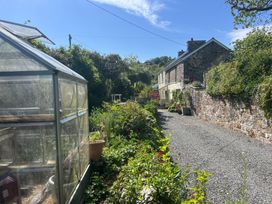 A garden with a greenhouse and gravel path at Penally Mews in St Dogmaels