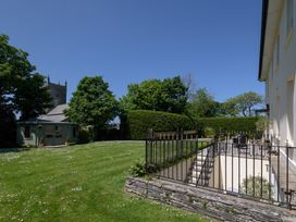 A garden with a house and church in the background at The Old Vicarage in St Issey