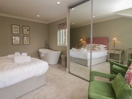 A bedroom with a bed, bathtub, and green chair at The Boundary in Windermere