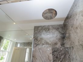 A bathroom with a shower head and tiled walls at The Boundary in Windermere