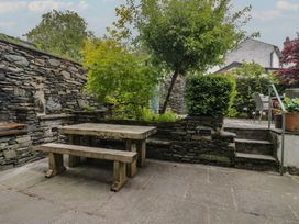 A garden with a stone wall and a wooden table at The Boundary in Windermere