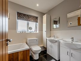 A bathroom with a bath tub and two wash basins at Sea Haze in Tenby
