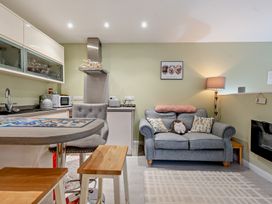 A living room with a sofa and kitchenette at Sea Haze in Tenby