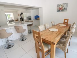 A dining room with a wooden table and bar stools at Sea Haze in Tenby