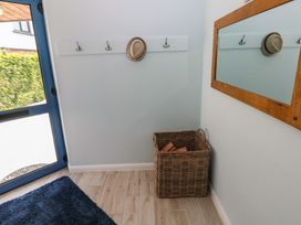 A hallway featuring hooks, a mirror, and a basket at Sea Haze in Tenby