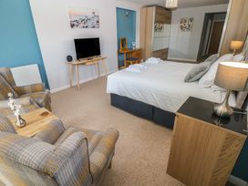 A bedroom with a bed, television, and seating area at Sea Haze in Tenby