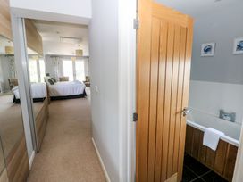 A bathroom with a bathtub and door at Sea Haze in Tenby