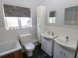 A bathroom with a bathtub, toilet, and sinks at Sea Haze in Tenby