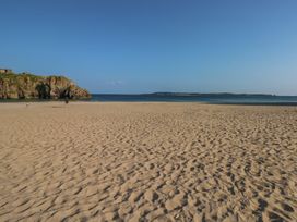 A beach with sand and a person walking at Sea Haze in Tenby