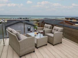 An outdoor seating area with drinks and a sea view at Lodge 1 Norwich