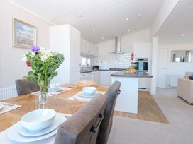 A dining room with a table set and kitchen in Sandy Snug Bacton