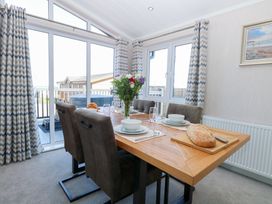 A dining room with a table set for meals at Sandy Snug in Bacton