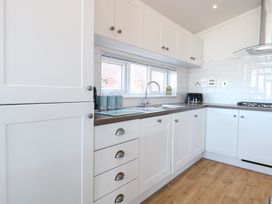 A kitchen with cabinets and appliances at Sandy Snug in Bacton