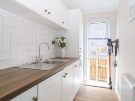 A laundry room with a sink and cabinets at Sandy Snug in Bacton