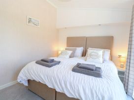 A bedroom with a bed, towels, and a bedside table at Sandy Snug in Bacton