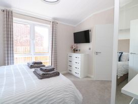 A bedroom with a bed, towels, tv and window at Sandy Snug in Bacton
