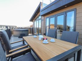 An outdoor seating area with a table and chairs near a hot tub at Sandy Snug in Bacton