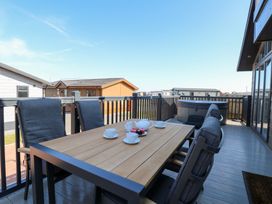 An outdoor deck with a table and chairs at Sandy Snug in Bacton