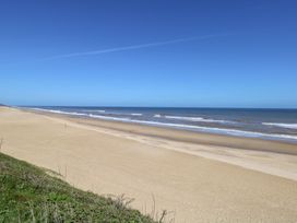 A beach with sand and ocean waves at Sandy Snug in Bacton