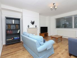 A living room with a sofa, armchair, coffee table, and television at Tan Y Mynydd in Dwygyfylchi