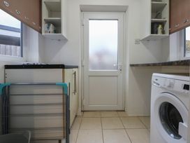 A laundry room with a washing machine and shelves at Tan Y Mynydd Dwygyfylchi
