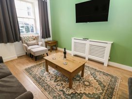 A living room with an armchair and table at Salvin Cottage in Alston