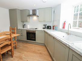 A kitchen with cabinets, counter, oven, sink, table, and chairs at Salvin Cottage in Alston