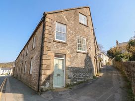 A stone building with windows and a door on a street at Salvin Cottage in Alston