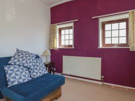 A living room with a blue sofa and patterned cushions at The Loft in Probus