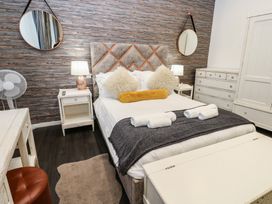 A bedroom with a bed, nightstand, desk, and drawers at The Railway Apartment in Hexham