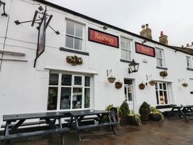 An outdoor hotel sign and benches at The Railway Apartment in Hexham
