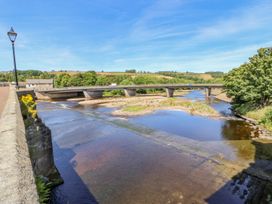 A view of a river with a bridge and trees at The Railway Apartment in Hexham